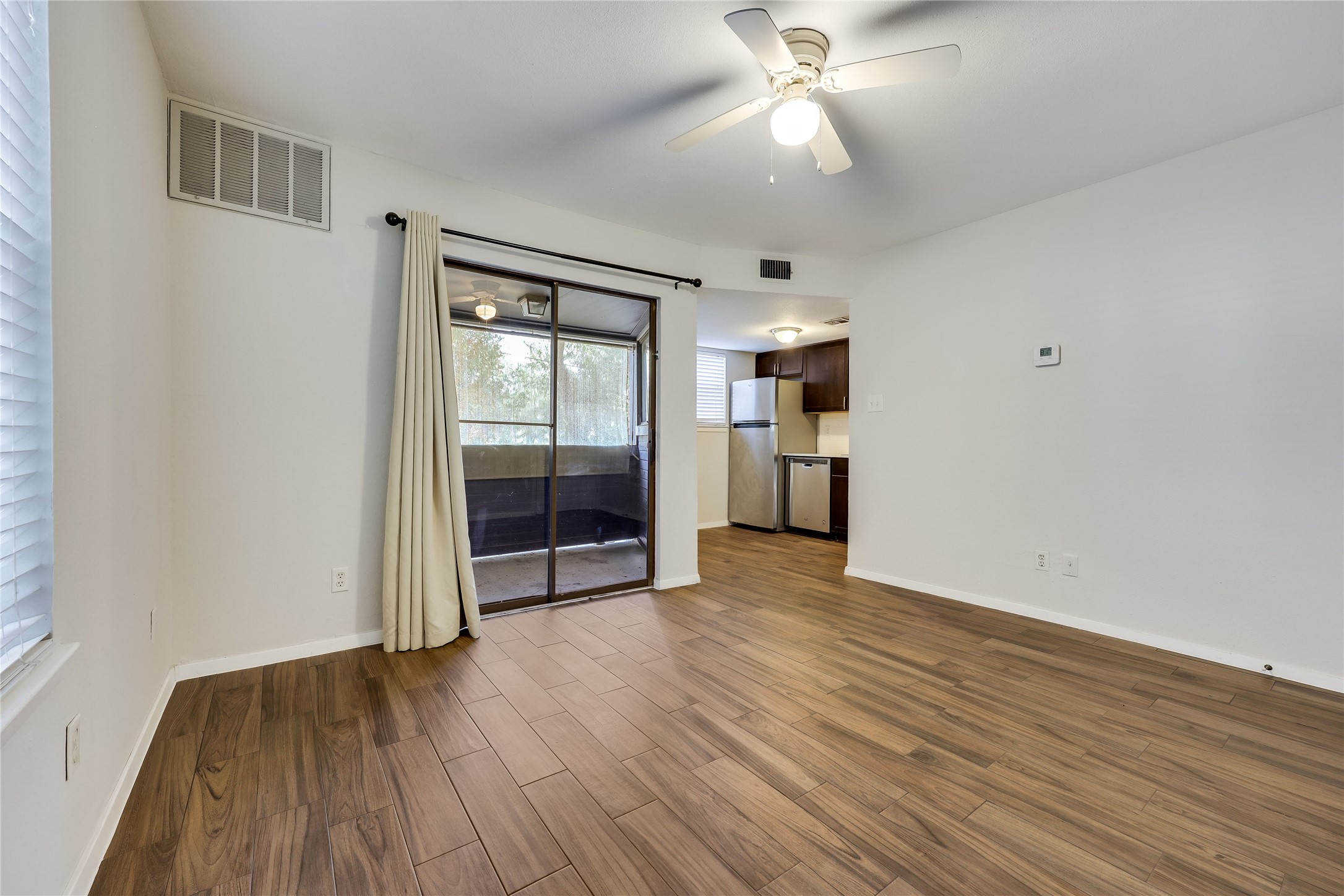 2500 Burleson Road, Unit 609 Austin, TX 78741 - Photo 14 of 32 Wood-look tile flooring unites the living area and leads to a balcony through sliding glass doors.