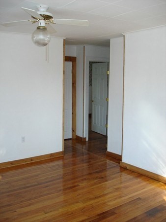 11-13 Colrain Street Greenfield, MA 01301 - Photo 6 of 10 a view of an empty room with wooden floor and a ceiling fan