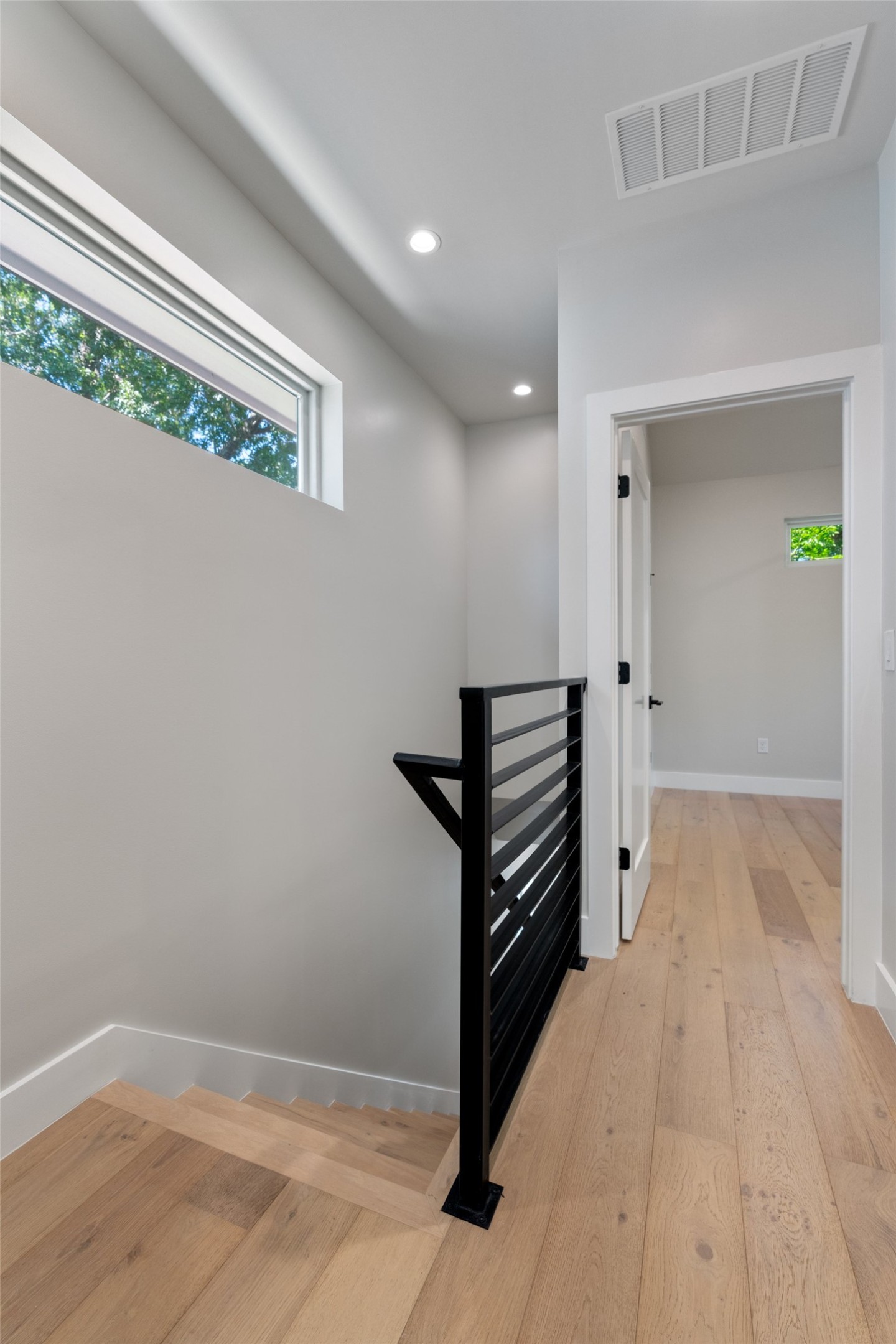 5200 Grover Avenue Austin, TX 78756 - Photo 14 of 32 Upstairs. Modern interior featuring light wood-finish flooring, recessed lighting, and a contemporary black metal stair railing