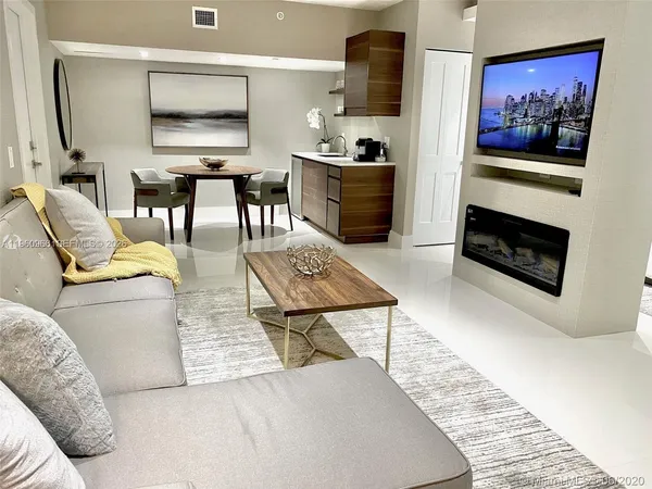 a living room with furniture a flat screen tv and kitchen view