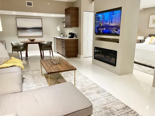a living room with furniture a flat screen tv and kitchen view