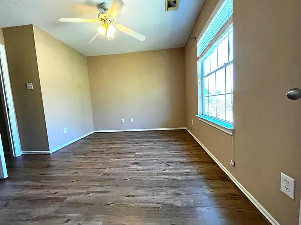 a view of an empty room with window and wooden floor
