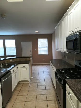 a kitchen with granite countertop a stove a sink and a microwave