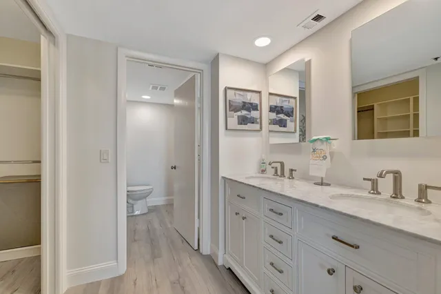 a spacious bathroom with a granite countertop sink a toilet and a mirror