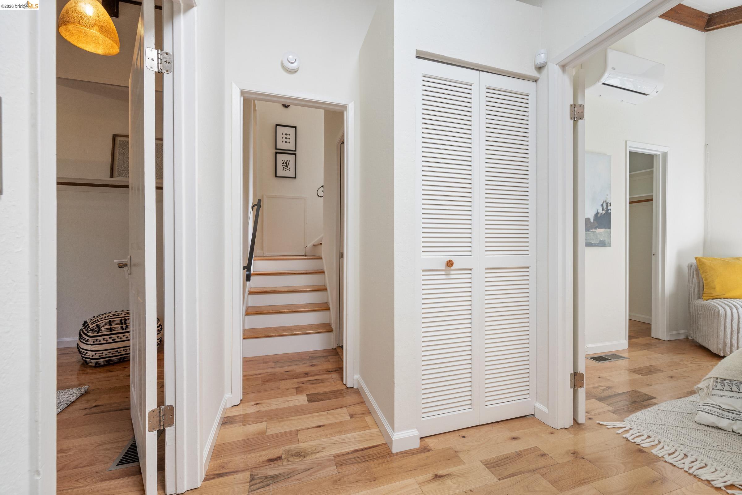 6600 Heather Ridge Way Oakland, CA 94611 - Photo 35 of 66 Hardwood-finish flooring throughout, featuring a white louvered bifold closet door, and a staircase with a black metal handrail