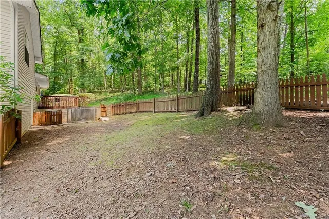 a view of a backyard with large trees and wooden fence