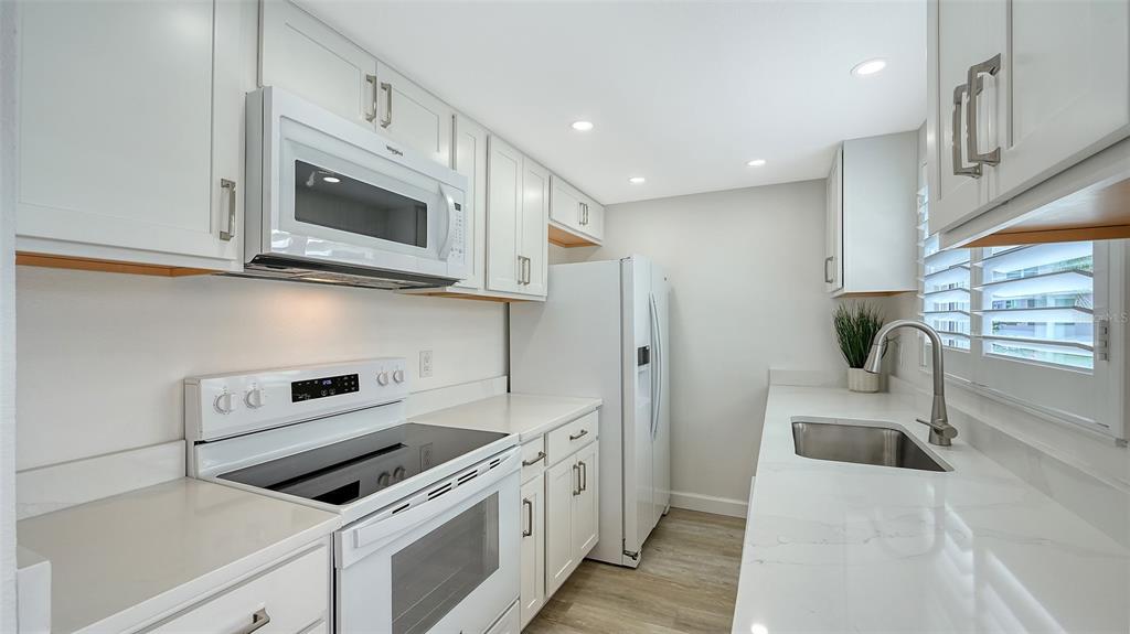 6020 Midnight Pass Road, Unit 63 Sarasota, FL 34242 - Photo 13 of 52 a kitchen with stainless steel appliances white cabinets and a stove top oven