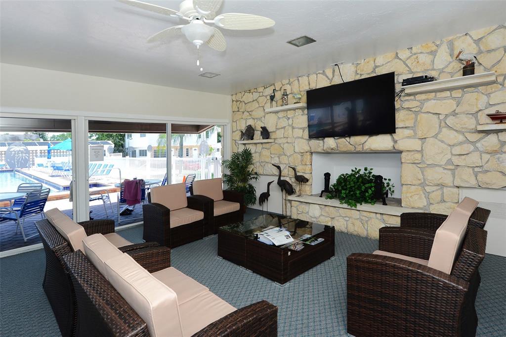 6020 Midnight Pass Road, Unit 63 Sarasota, FL 34242 - Photo 24 of 52 a living room with furniture a flat screen tv and a floor to ceiling window