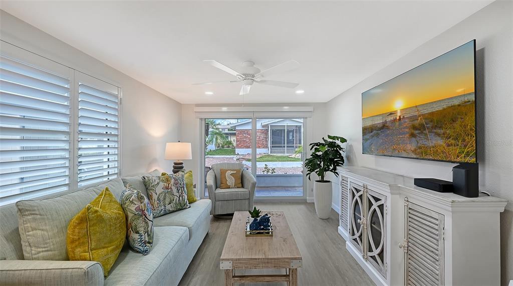 6020 Midnight Pass Road, Unit 63 Sarasota, FL 34242 - Photo 8 of 52 a living room with furniture a flat screen tv and a floor to ceiling window