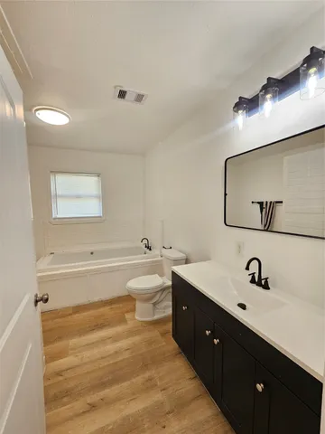 a spacious bathroom with a double vanity sink a toilet and a bathtub