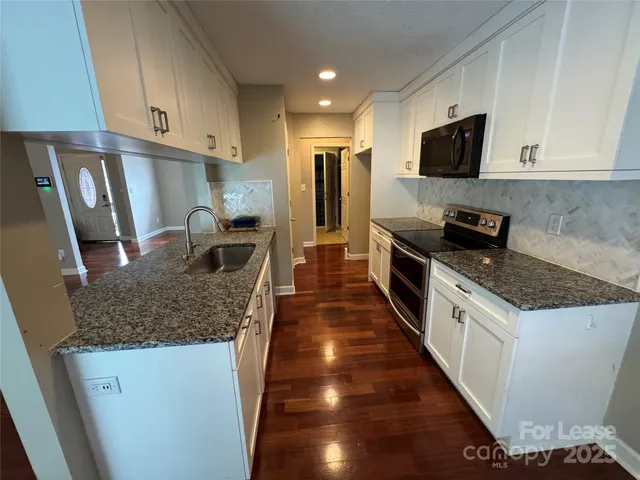 a kitchen with granite countertop a sink a counter top space stainless steel appliances and cabinets