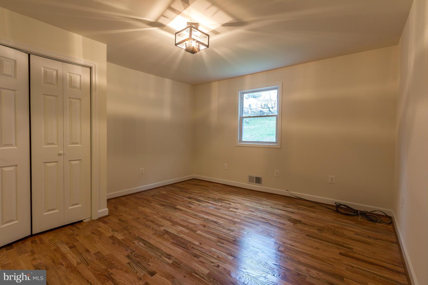 4503 Mahan Road Silver Spring, MD 20906 - Photo 9 of 25 an empty room with wooden floor chandelier fan and windows