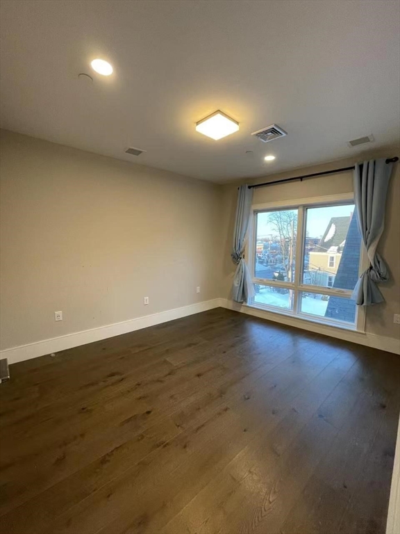 214 Market Street, Unit 301 Boston, MA 02135 - Photo 7 of 11 an empty room with wooden floor and windows