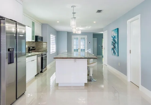 a kitchen with kitchen island a counter top space stainless steel appliances and cabinets