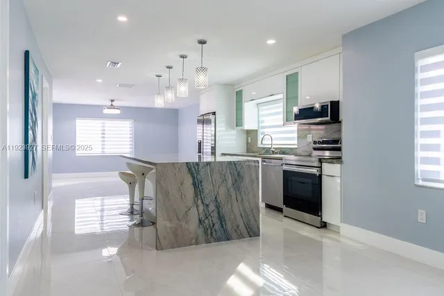 a kitchen with stainless steel appliances granite countertop a refrigerator a sink a stove top oven a sink and a window