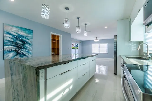 a kitchen with granite countertop a stove a sink and a refrigerator