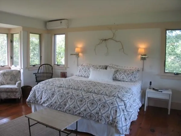 a bedroom with a bed and a large window with chair