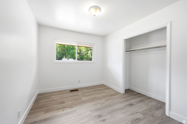 936 Chatelain Road Ogden, UT 84403 - Photo 15 of 33 Bright secondary bedroom featuring wood-finish flooring, a generous closet with sliding doors, and a large window allowing natural light throughout the space