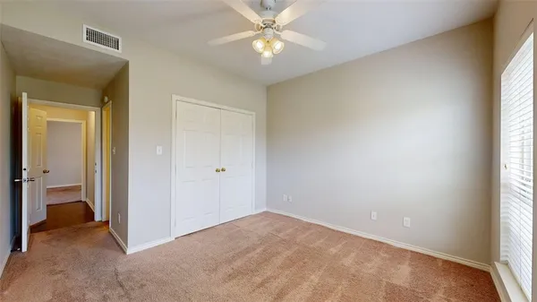 a view of an empty room and window and chandelier fan