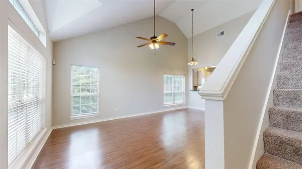 a view of empty room with wooden floor and fan