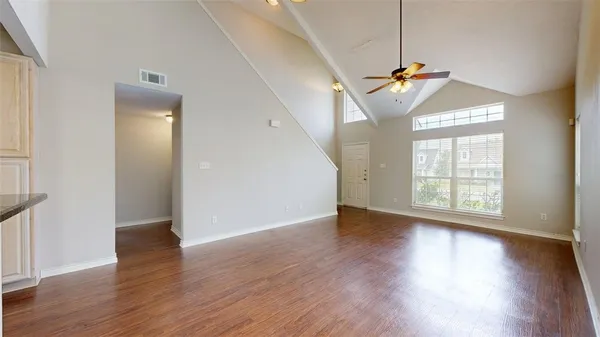 an empty room with wooden floor and windows