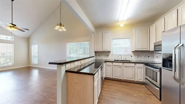 a kitchen with stainless steel appliances granite countertop a sink a stove and refrigerator