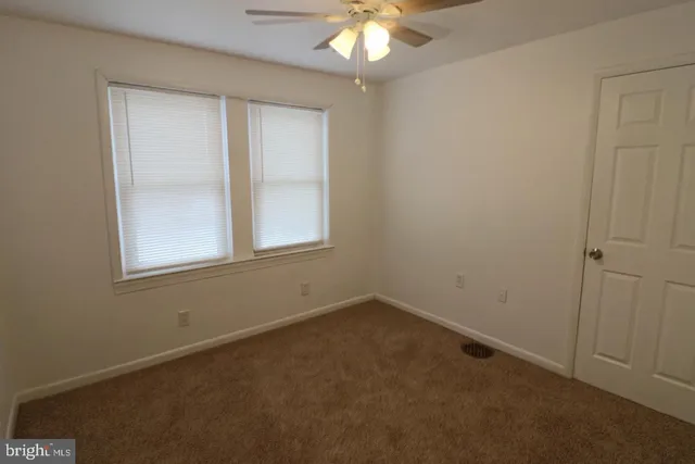 an empty room with a chandelier fan and windows