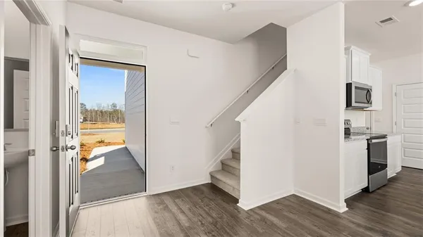 a view of a hallway with wooden floor and a kitchen space