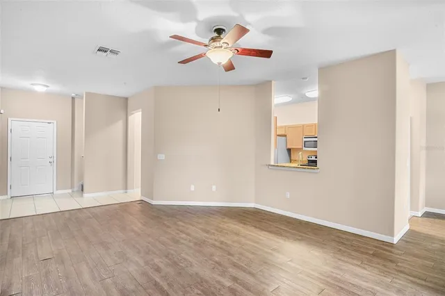 an empty room with wooden floor and ceiling fan
