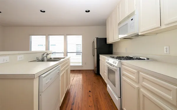 a kitchen with granite countertop a sink a counter space appliances and cabinets