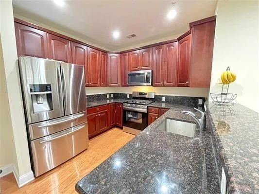 a kitchen with granite countertop stainless steel appliances a refrigerator a stove top oven and cabinets