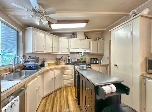 a kitchen with a sink a stove a refrigerator cabinets and a window
