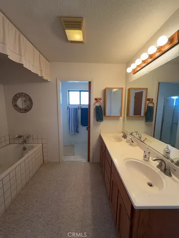 a spacious bathroom with a double vanity sink a mirror and a bathtub