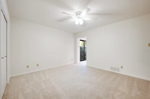 an empty room with chandelier fan and windows