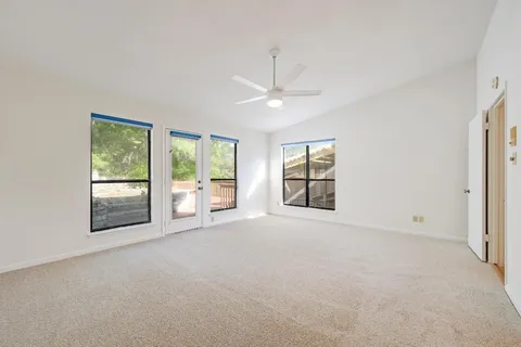 an empty room with windows and ceiling fan