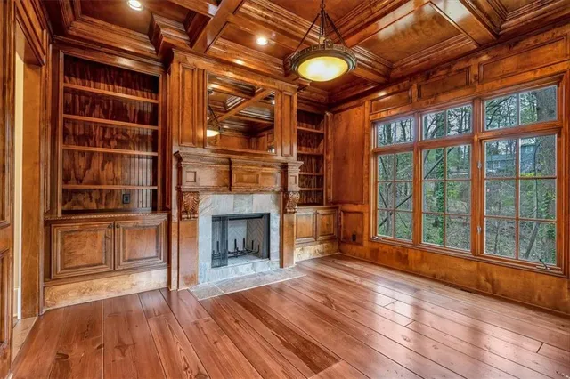 a view of an empty room with wooden floor fireplace and a window