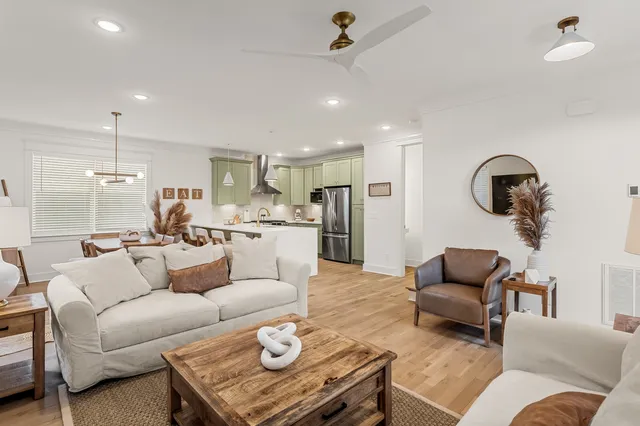 a living room with furniture kitchen view and a wooden floor