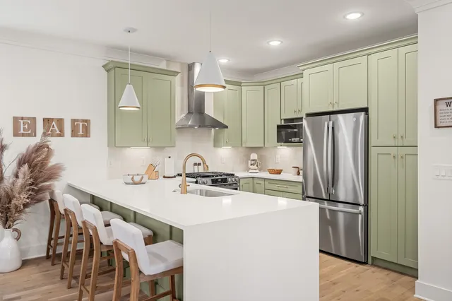 a kitchen with a sink a refrigerator and a stove top oven with wooden floor