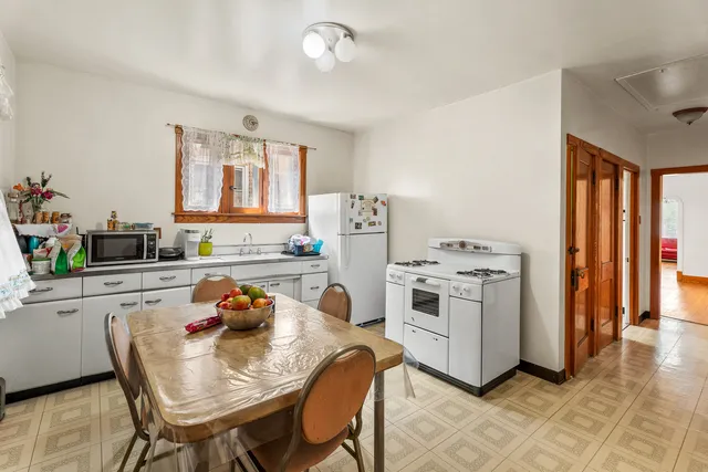 a white kitchen with a stove a refrigerator and a dining table