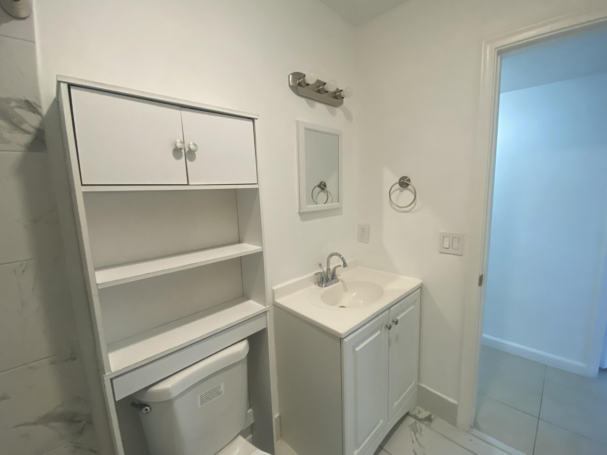 298 Southwest 6th Street, Unit 109 Boca Raton, FL 33432 - Photo 9 of 28 a bathroom with a sink a toilet and a mirror