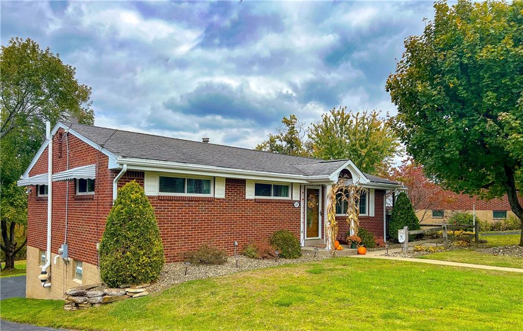 a front view of house with yard and trees in the background