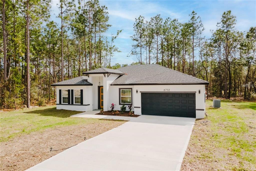 6732 Southwest 132nd Street Ocala, FL 34473 - Photo 2 of 36 a front view of a house with a yard and trees
