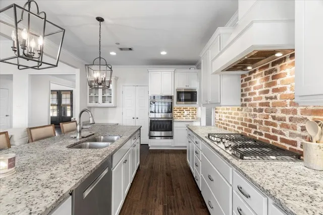 a large kitchen with granite countertop a sink a counter space appliances and cabinets