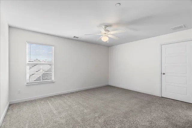 an empty room with windows and fan