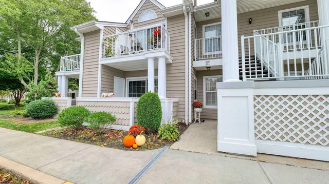 front view of a brick house with a large window and potted plants