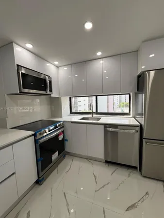 a kitchen with granite countertop a refrigerator and a stove top oven