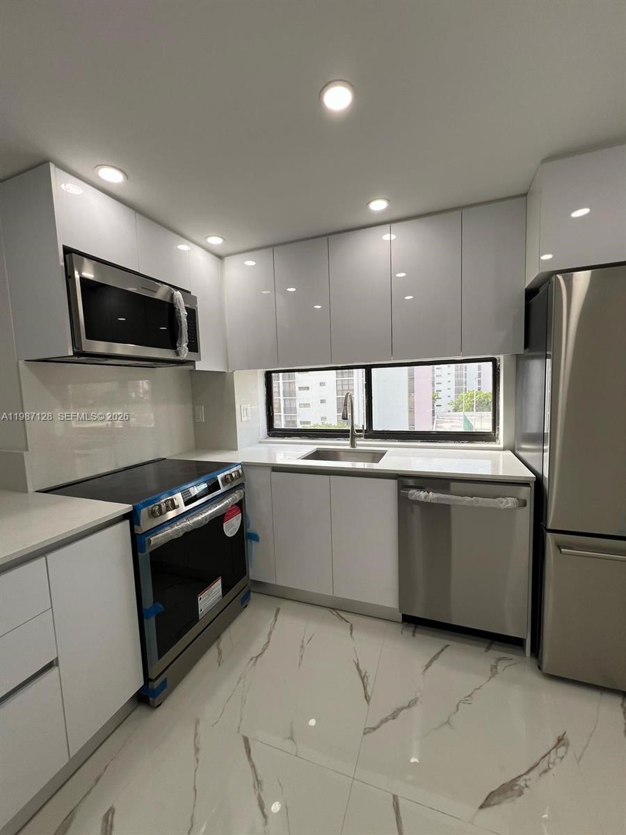 16909 North Bay Road, Unit 710 Sunny Isles Beach, FL 33160 - Photo 2 of 19 a kitchen with granite countertop a refrigerator and a stove top oven