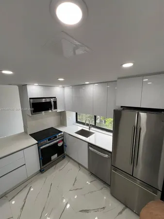 a large kitchen with stainless steel appliances granite countertop a refrigerator and a stove top oven