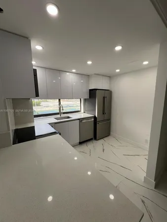 a large white kitchen with stainless steel appliances a refrigerator and a stove top oven