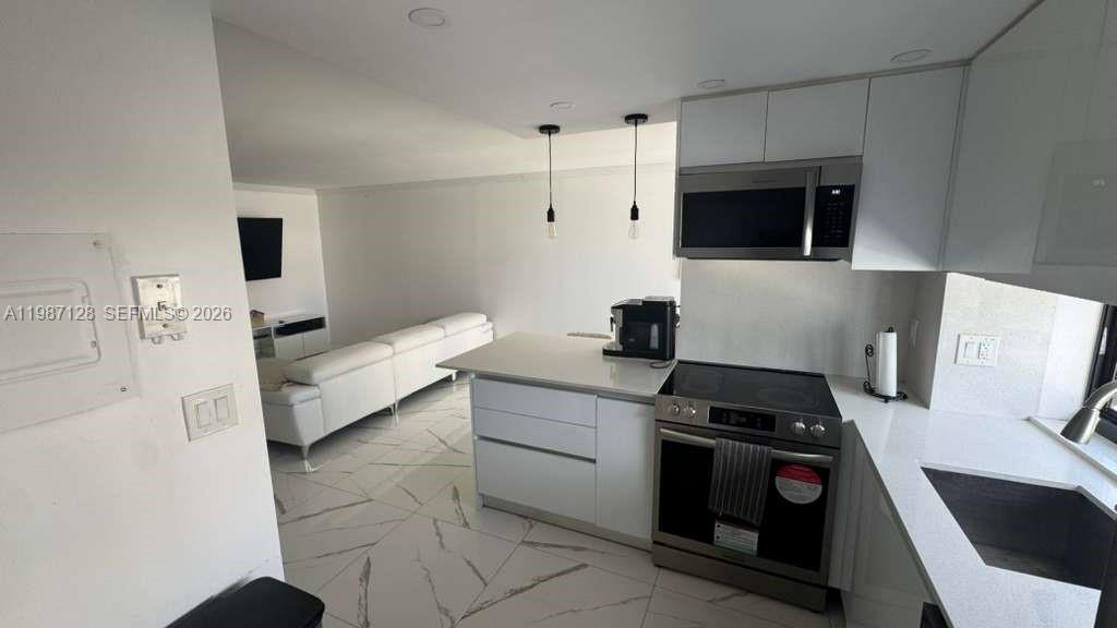 16909 North Bay Road, Unit 710 Sunny Isles Beach, FL 33160 - Photo 7 of 19 a kitchen with stainless steel appliances a stove a microwave and a refrigerator